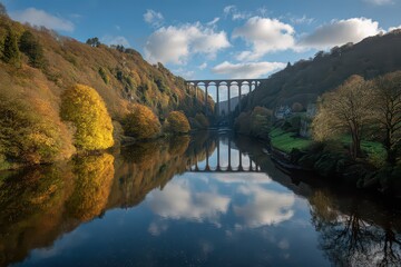 Carmine River Flanked by Forest in Autumn under Cloudscape Reflected on River with Tall Stone Arch Railway Bridge against Blue Sky