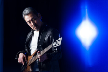Fototapeta premium ライブハウスのステージでベースを演奏するバンドマンの中高年男性