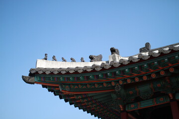 Traditional Korean Palace Roof with Guardian Figures against Blue Sky