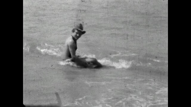 Playful man fooling around on summer sea beach. Funny crazy vacationer enjoying seaside vacation. Humorous fun travel in carefree leisure by ocean. Old film. Archival retro 1970s. Vintage archive