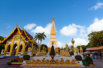 Fototapeta premium Phra That Phanom Stupa through Ornate Temple Door, Nakhon Phanom, Thailand,A wide-angle shot of the iconic Phra That Phanom pagoda framed by golden carved wooden doors at Wat Phra That Phanom.