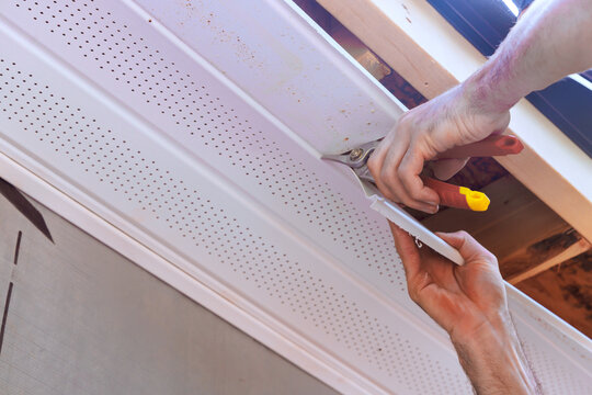Person installs ceiling trim using tools in room