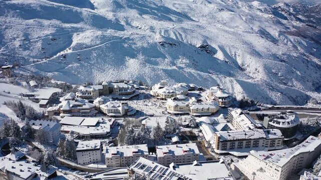 Aerial 4K video from a drone to Sierra Nevada ski resort on a sunny winter day in the mountains, Spain. Sierra Nevada is the largest mountain range near the city of Granada in Spain with snow. Sierra 