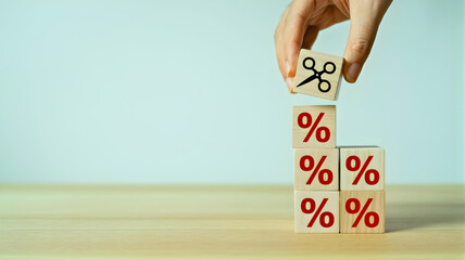 Hand places scissors block on percentage rate cubes, symbolizing financial reduction, interest rate cuts, and smart discount strategies for economic growth
