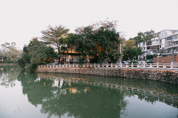 Obraz premium Tranquil River Scene with Traditional Buildings and Tree Reflections - Huizhou West Lake