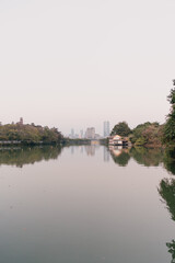 Obraz premium Calm Lake Reflecting City Skyline and Trees at Dusk - Huizhou West Lake