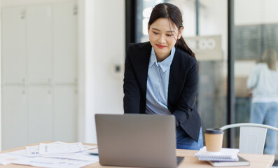 Fototapeta premium Business asian woman working on laptop and send information to her team, the marketing team leader is reviewing documents related to marketing data 