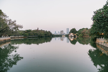 Fototapeta premium Serene Lake Reflection with City Skyline in the Distance, West Lake in Huizhou, Guangdong Province, Asia China, is a tourist attraction featuring ancient architecture