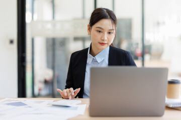 Fototapeta premium Focused Female Professional Working on Laptop at Desk 