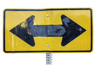 Weathered yellow road sign with two black arrows pointing left and right, indicating a two-way...