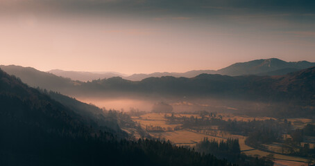 sunrise in the mountains with a mist rising over a valley.