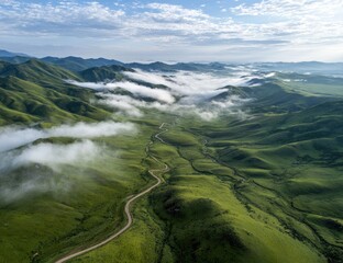 Lush green hills, misty valley, winding road, aerial view