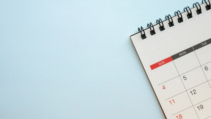 Top view of blank spiral desk calendar on light blue background with ample copy space for scheduling