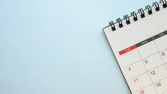 Top view of blank spiral desk calendar on light blue background with ample copy space for scheduling