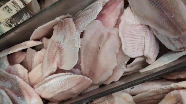 Fish filleting process at a local market showing hands and fresh fish being prepared