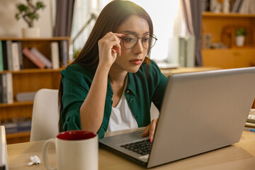 Stressed young woman adjusting glasses while looking at laptop screen working seriously feeling tired or confused having vision problem