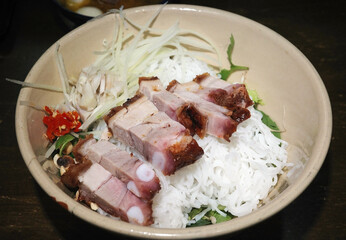 authentic bun mam nem bowl with crispy roast pork belly. da nang local fermented fish sauce vermicelli. central vietnamese cuisine with green papaya and chili.
