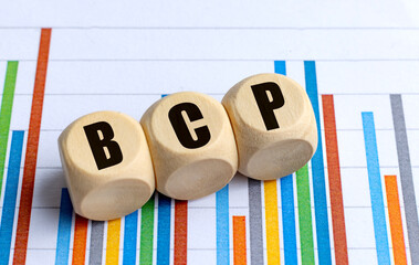 BCP Business Continuity Plan concept on round wooden blocks over colorful bar chart background