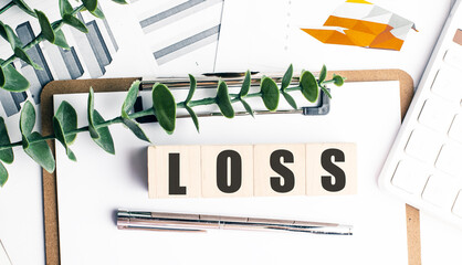Loss concept on wooden blocks with charts, clipboard, pen, calculator and green plant