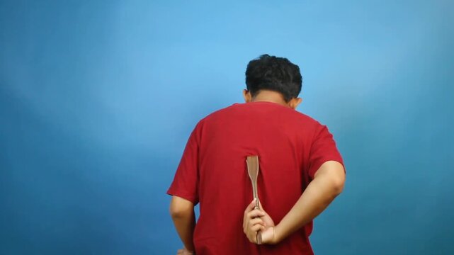 Asian man scratching itchy back with scratcher isolated on blue background