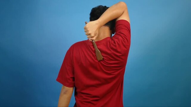 Asian man scratching itchy back with scratcher isolated on blue background