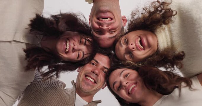 Happy friends group standing in circle, hugging each other and looking down at camera together. Cooperation, joy and teamwork of cheerful people smiling in portrait, celebrate team unity, friendship