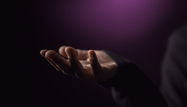 Open hand reaching in darkness. Concept of poverty, inequality, humanitarian aid
