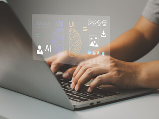 Person typing on laptop keyboard with virtual AI, UX and UI brain interface overlay conveying creative design and technology collaboration, focused professional hands and workspace