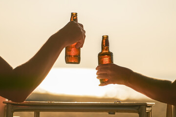 Friends or a couple drink beer and relax on the beach. Two bottles of beer in his hands on the...