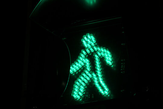 Green light for pedestrians. The "walk" symbol on a traffic signal, indicating it is safe to cross the street. A concept of safety, urban life, and traffic regulation.