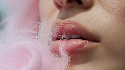 Fototapeta premium Woman's lips with pink cotton candy, sweet and tempting closeup