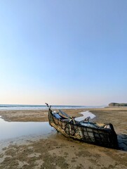Traditional Wooden Fishing Boat Rested on Sandy Beach at Low Tide