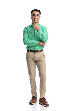 Happy young man touching chin and smiling comfortably