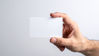 Fototapeta premium Hand male hand white card blank card business card mockup copy space closeup human finger neutral background Clean closeup of male hand holding white blank business card mockup with copy space
