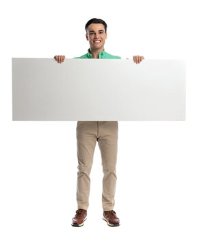 Happy casual man holding large blank board
