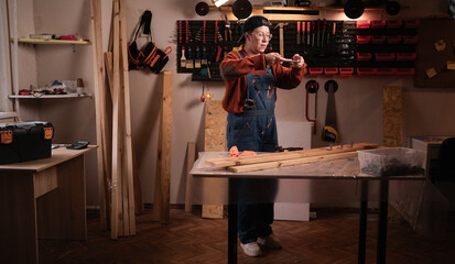 Female carpenter taking photos of handmade wooden hangers for website content in workshop at evening