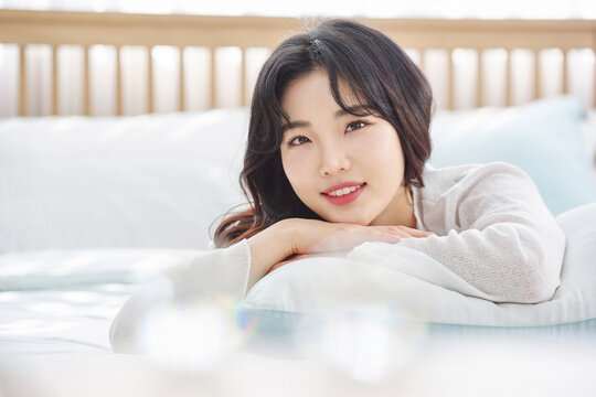 Relaxed Asian woman smiling softly in bed