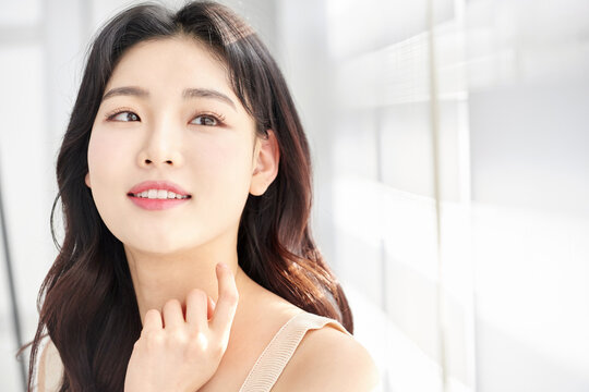 Young woman thoughtfully touching neck in soft light