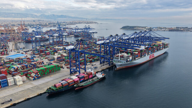 Aerial drone photo of industrial container terminal and small port of Perama with cranes loading - unloading from truck size container ships, Perama, Attica, Greece