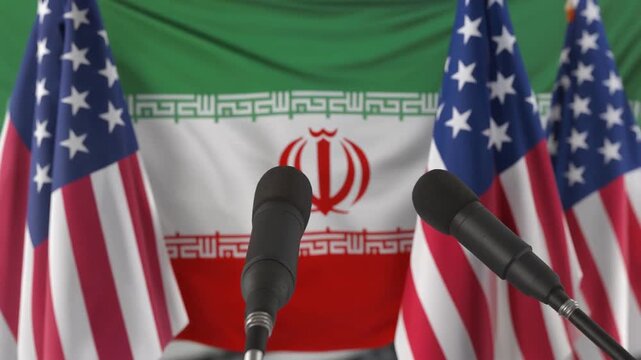 USA and Iran flags at diplomatic press conference with microphones.