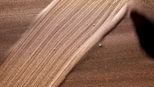 Dynamic close-up of paintbrush sweeping diagonal streaks across golden paint surface, highlighting fine linear texture left by brush and lifting action.
