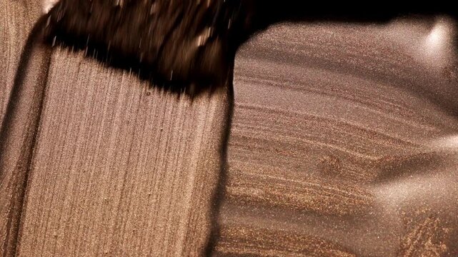 Vertical movement shot showing paintbrush creating strong parallel vertical streaks of golden paint, emphasizing layered texture and deep color contrast.