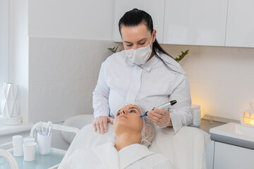 Caucasian adult woman girl receives microneedling treatment under eye area during fractional...