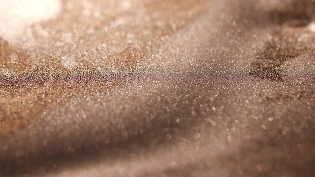 Macro shot of golden paint with shallow depth of field, emphasizing subtle shimmer and texture differentiation between blurry foreground and illuminated central plane.
