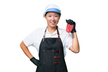 Young caucasian woman wearing an apron and serving fresh cut meat over isolated background posing with arms at hip and smiling