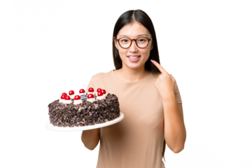 Young Asian woman holding birthday cake over isolated chroma key background giving a thumbs up gesture