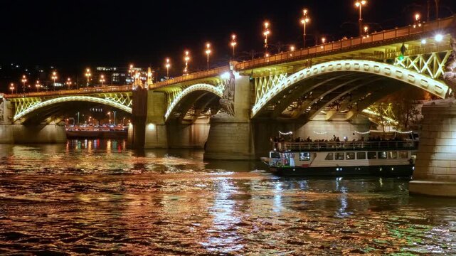 Stunning night view of the illuminated Margaret Bridge in Budapest, Hungary. The golden lights reflect beautifully on the Danube River surface, showcasing European architecture and city travel
