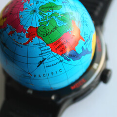Small model of Earth on a blurred black watch isolated on white square stock image. Global time and global problems conceptual stock photo 