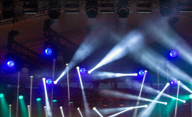 Colorful concert lights illuminate the stage during an energetic live music performance at an outdoor venue