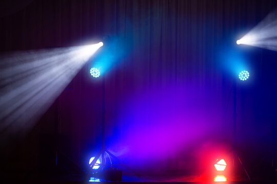 Colorful stage lighting with beams and fog creating an atmospheric effect at a live event venue